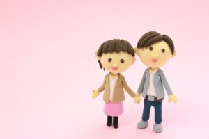 背景がピンクで女性と男性が手を繋いでいる