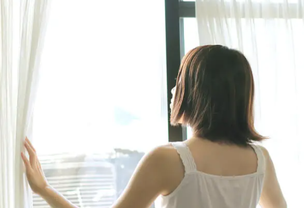 カーテンを開ける女性　カーテン　日差し